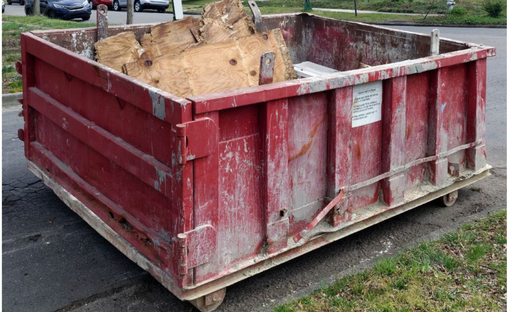 a red dumpster with wood inside sitting on a public road